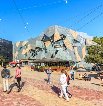 people walking through Federation Square looking at buildings
