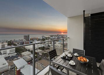 hotel balcony looking over Darwin with sun setting and ocean in background